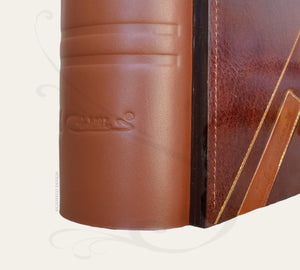signature on the brown leather spine of a photo book by Giovelli Design